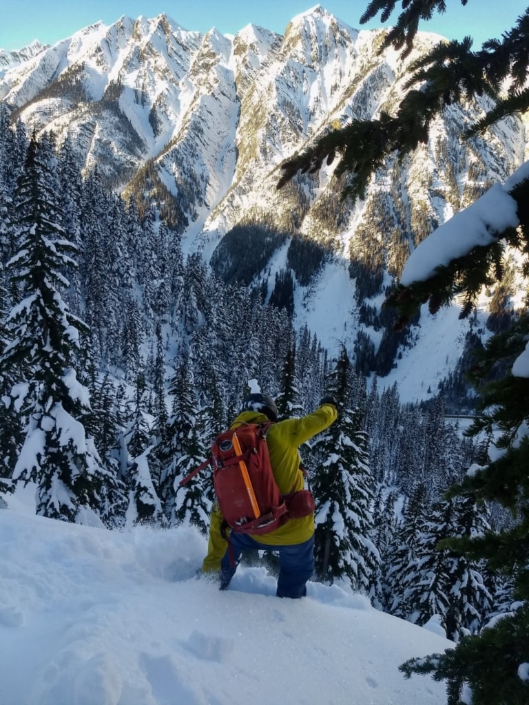 snowboarder slashing powder on the ross peak path with the cougars in the background