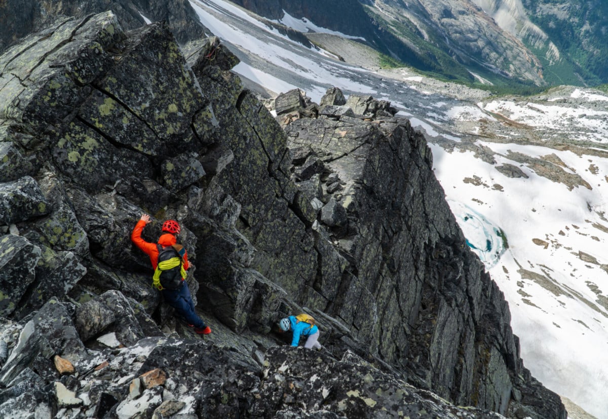 a man and a woman climbing a crux corner with exposure