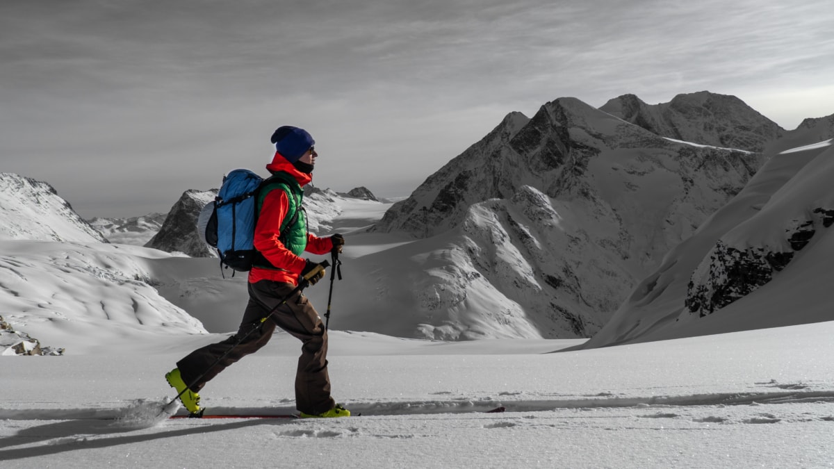 ski tourer making a big stride with grand mountains in the back