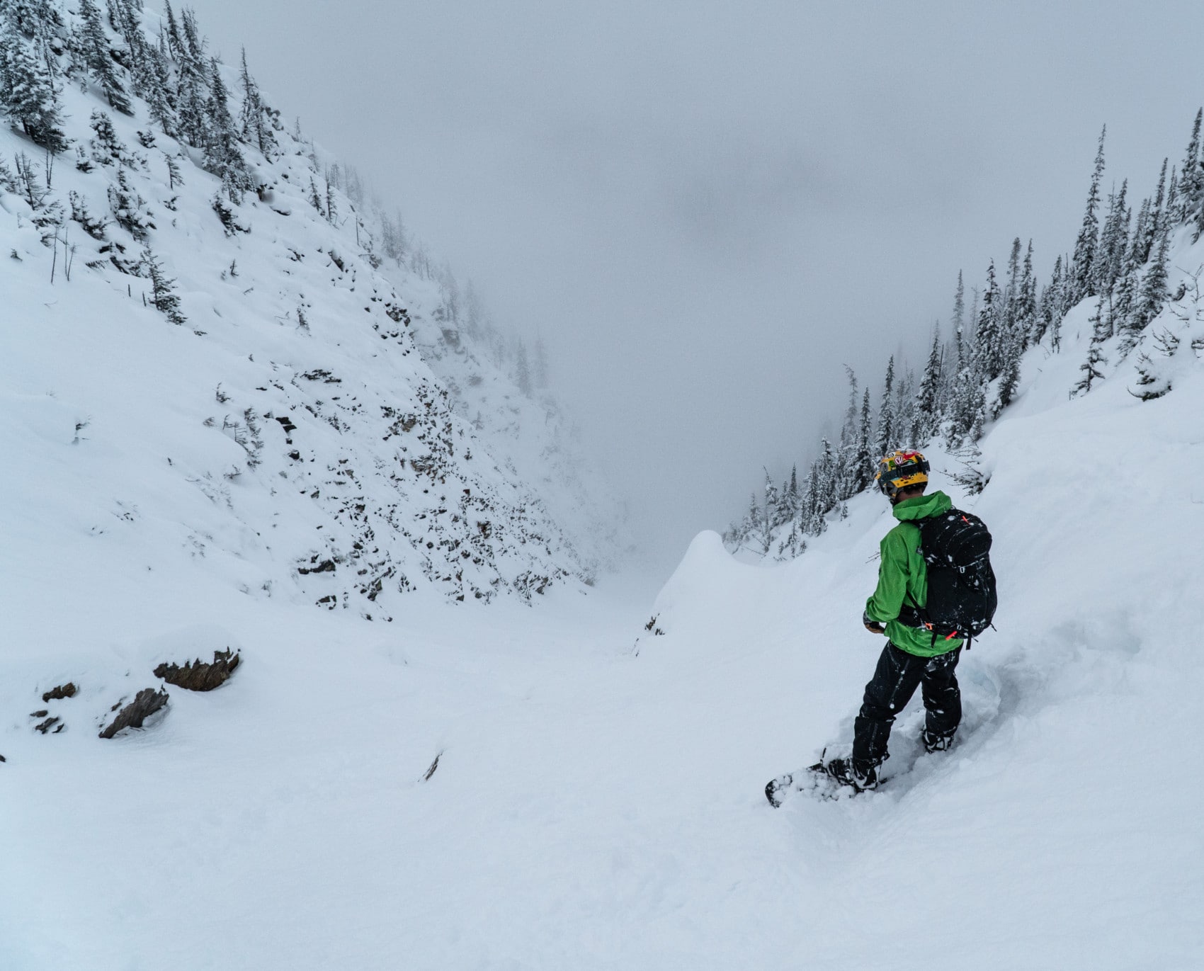 snowboarder scoping out the ross peak couloir with valley bottom clouds featured