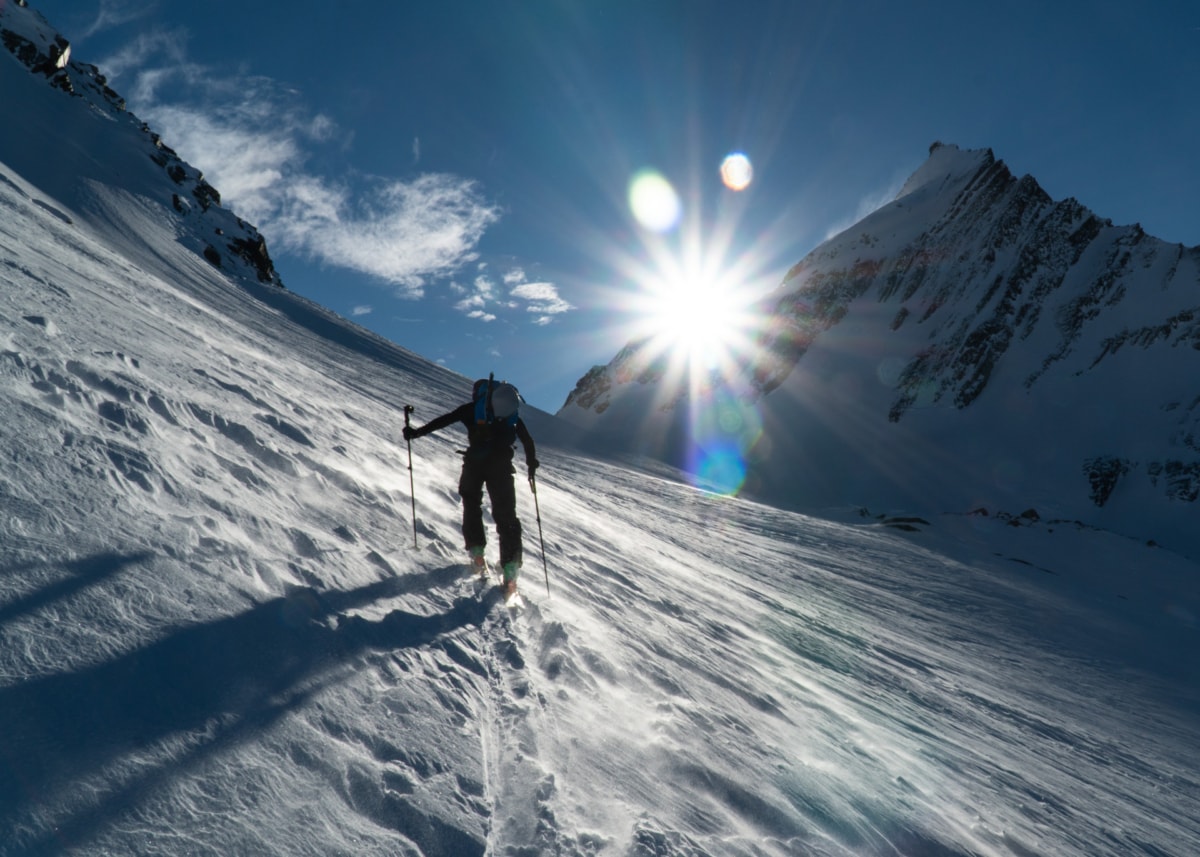 solo skier walking up the lily glacier in high winds