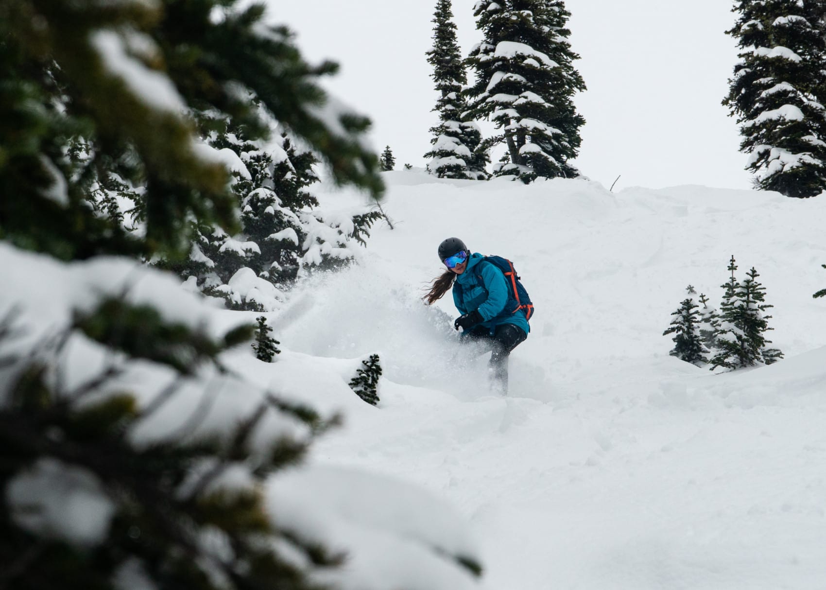 splitboarder slashing a turn down ursus trees featured