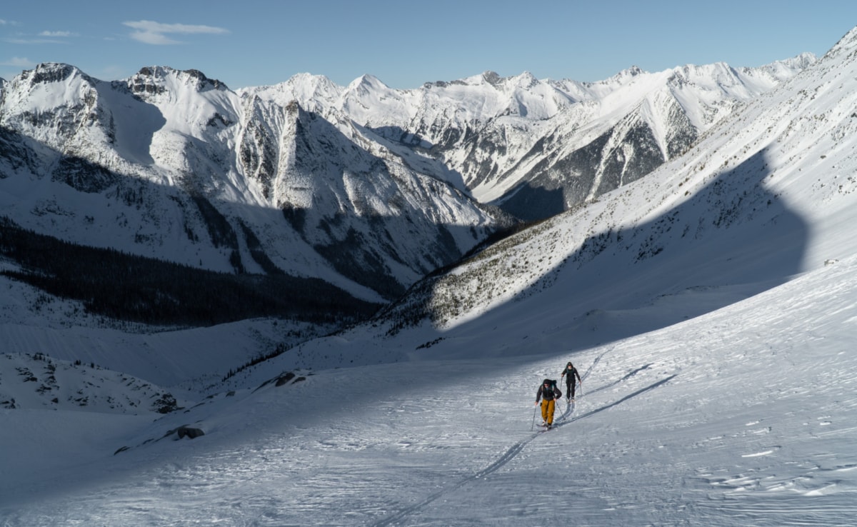 two male skiers walking up below the west slopes of mt afton