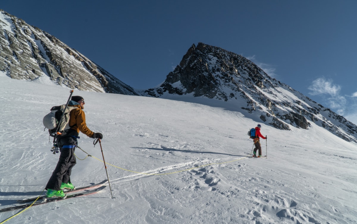 two roped up mountaineers walking towards the dome col