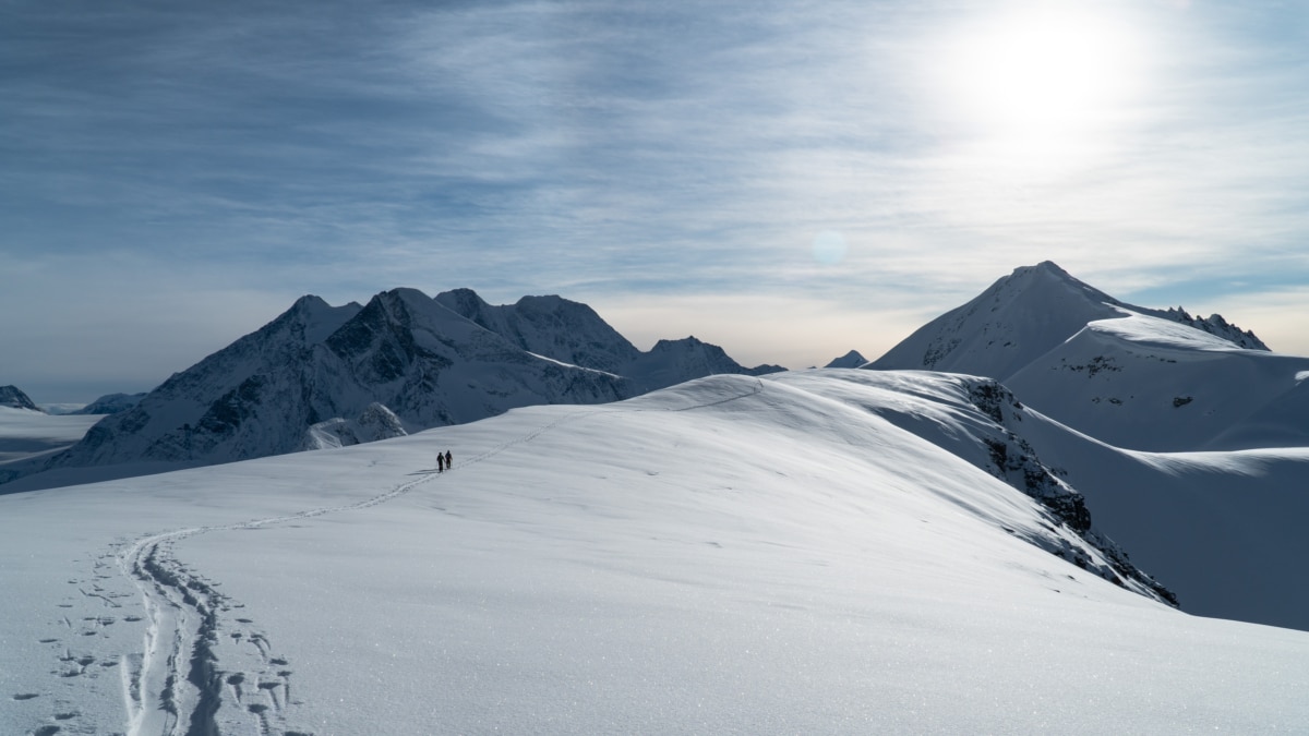 two skiers traversing the illecillewaet glacier on their way to forever young couloir