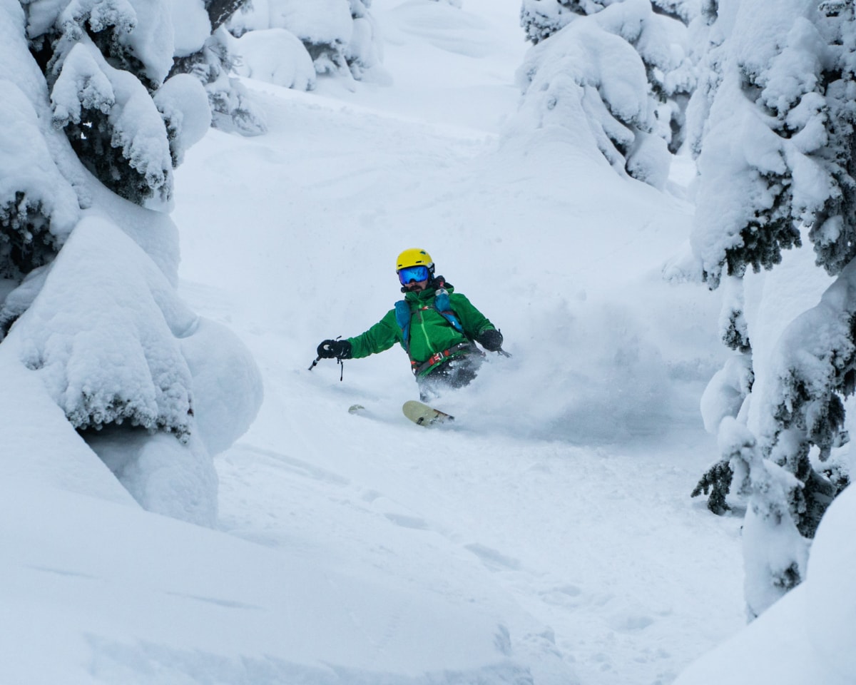 skier carving a turn through deep powder amongst trees 1