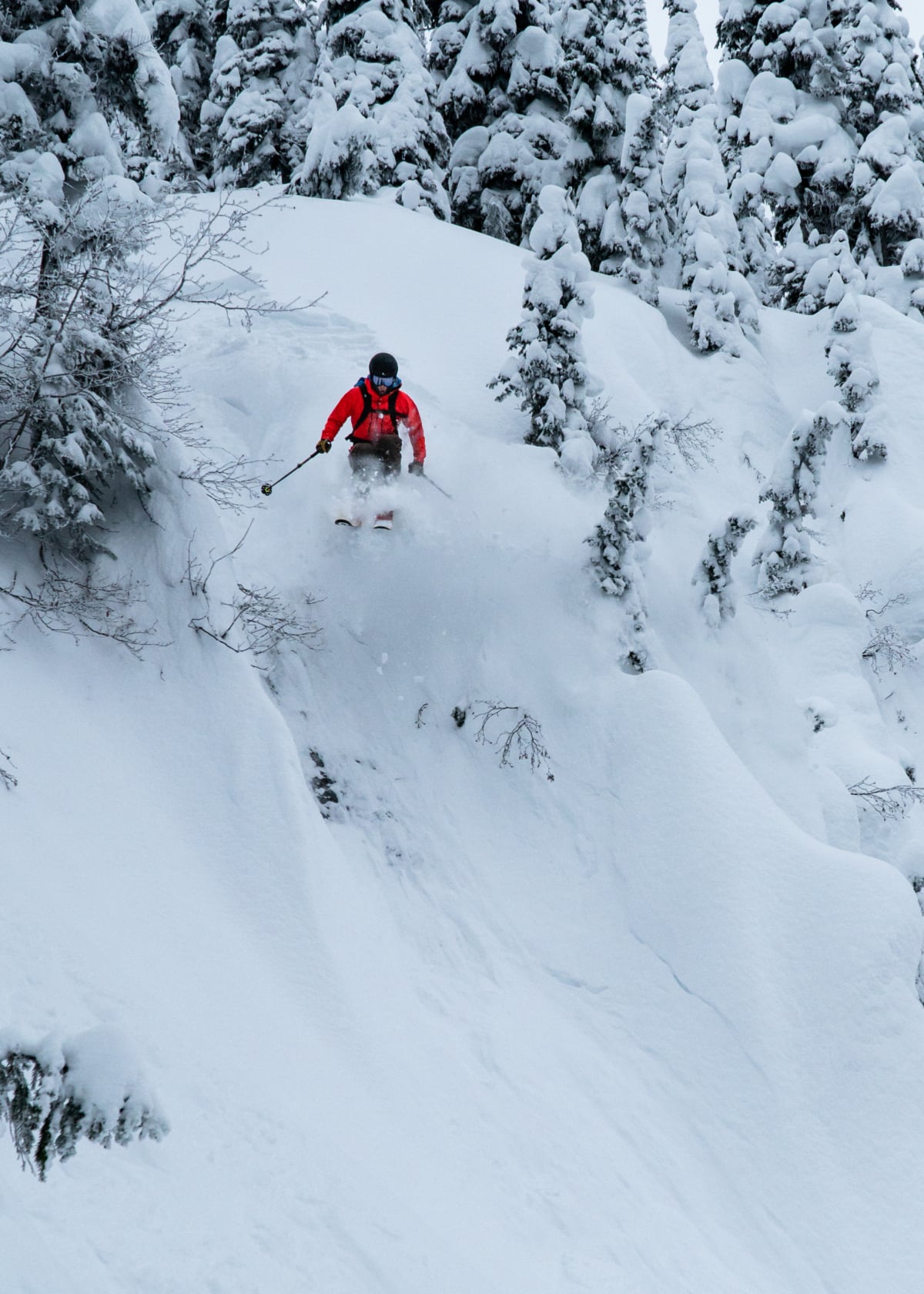 skier in red jacket jumping over ice patch in the begbie backcountry