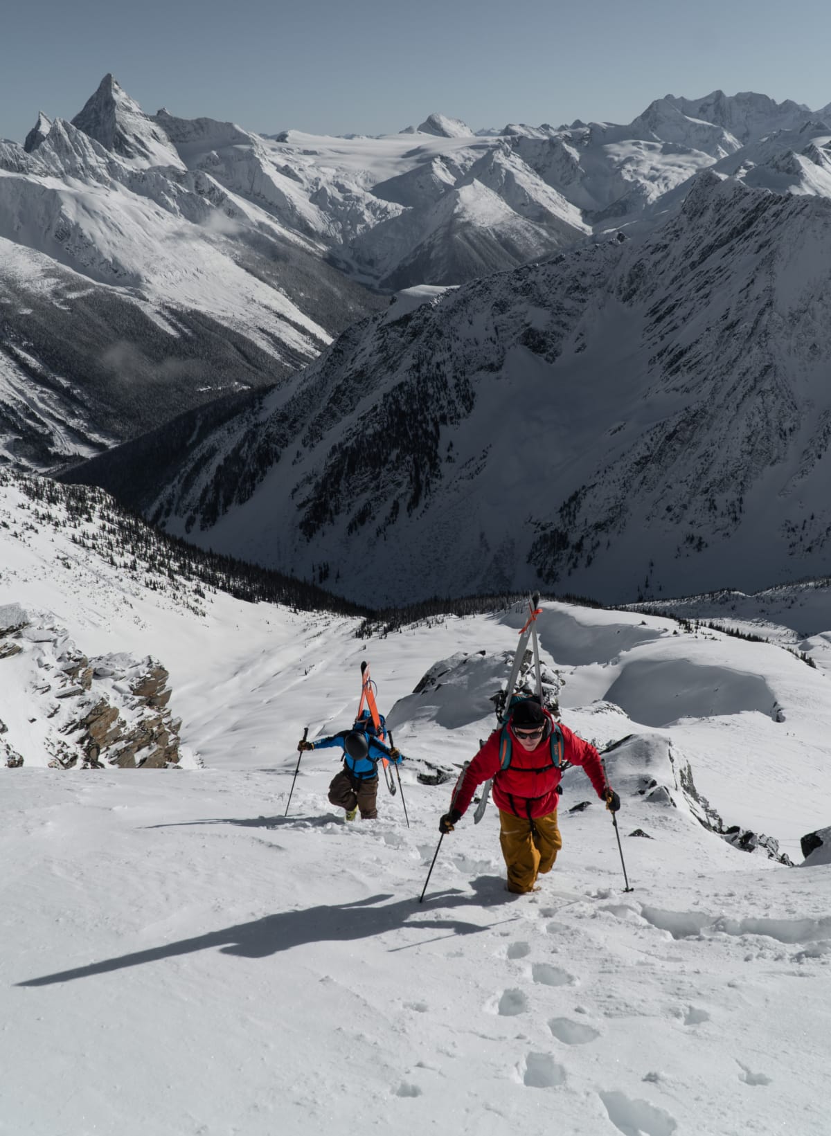 two skiers booting up a snowy slope