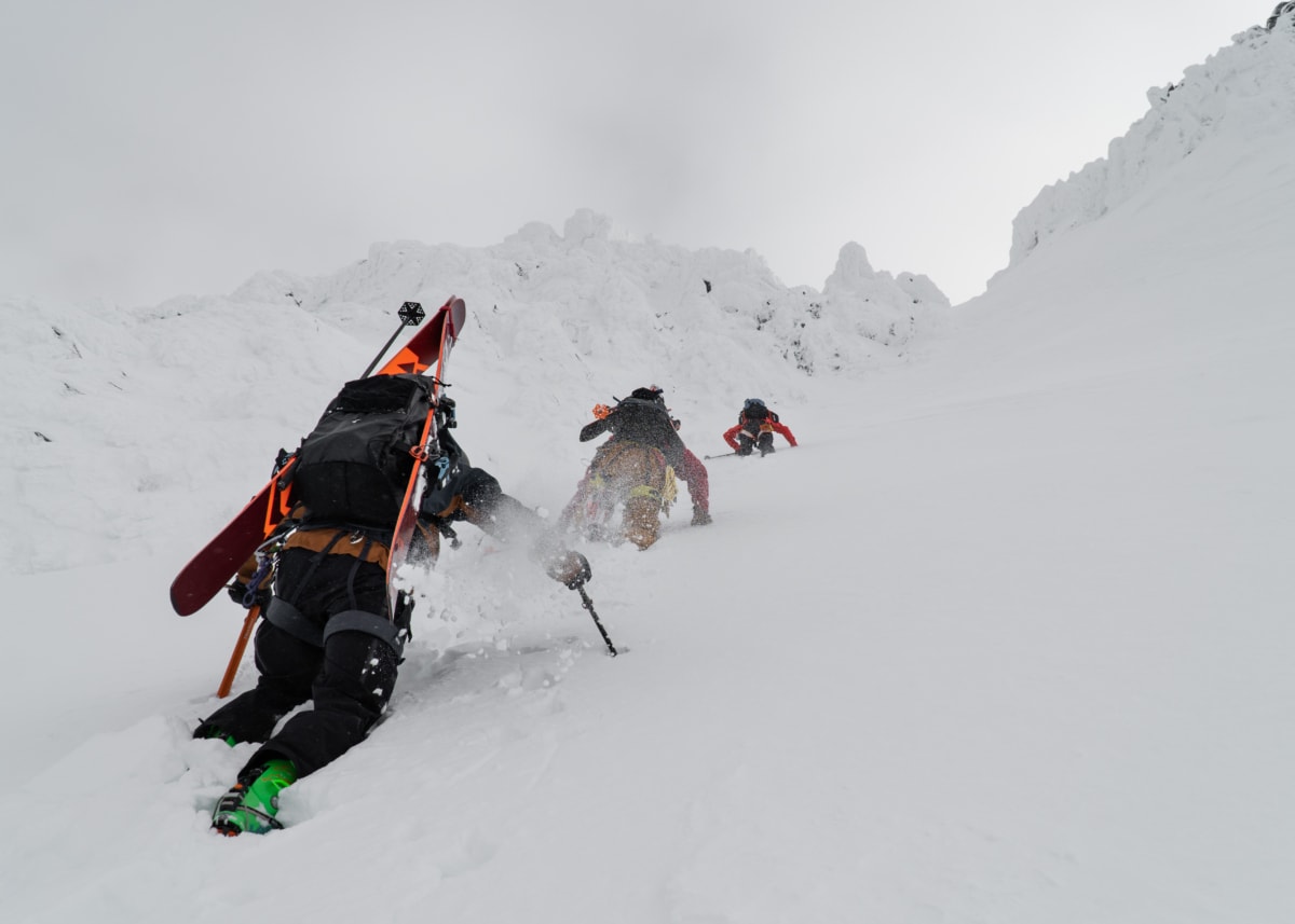 group of skiers with skis on their back climbing up the avalanche nw couloir