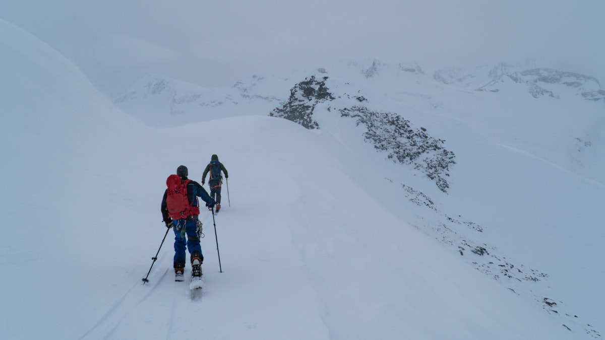 skier and snowboarders stuck on a windy ridge in a storm