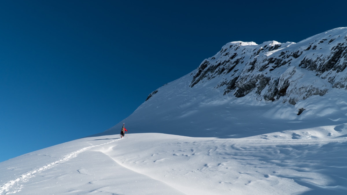 climber with skis booting up the north face of 8812