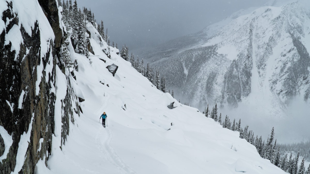 splitboarder walking along the top of the grizzly shoulder next to a rocky cliff