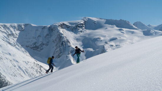 two skiers ascending wintery slopes of the abbott east slidepath