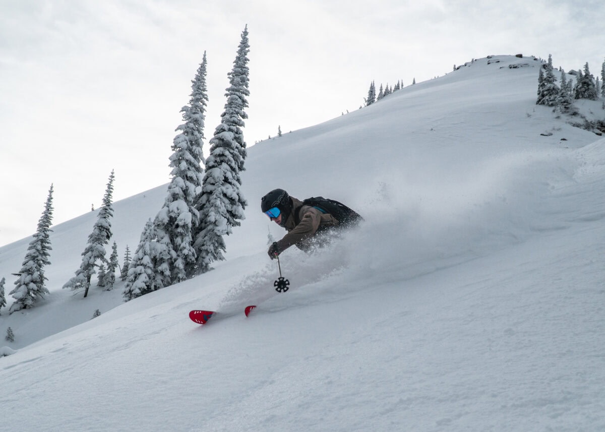 backcountry skier carving a deep turn above Greely Trees