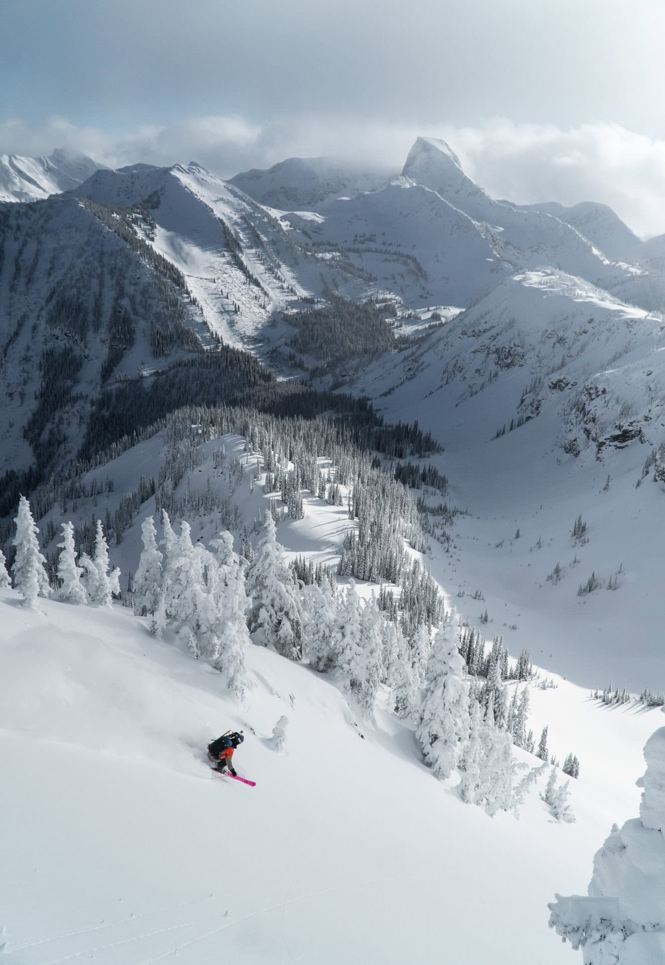 skier carving down the south face of montana peak, ghost peak in the back