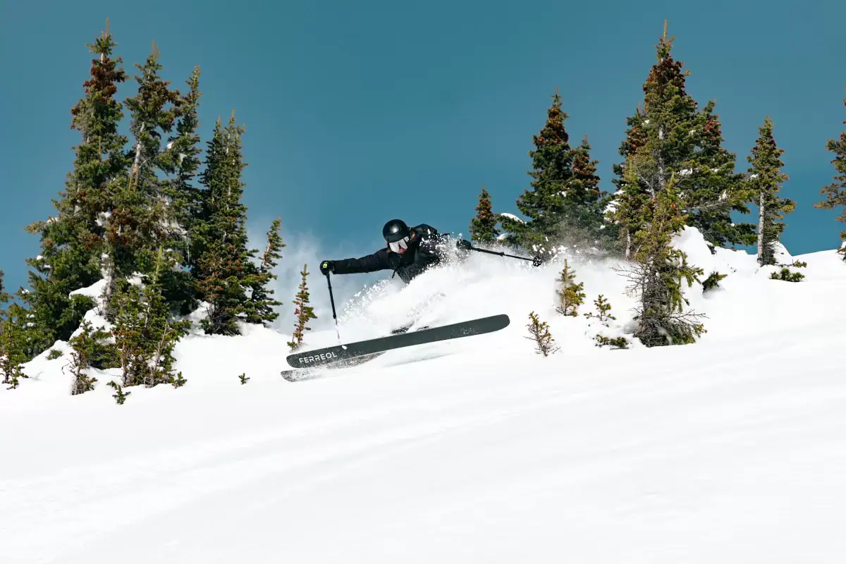 skier slashing powder amongst trees with ferreol skis
