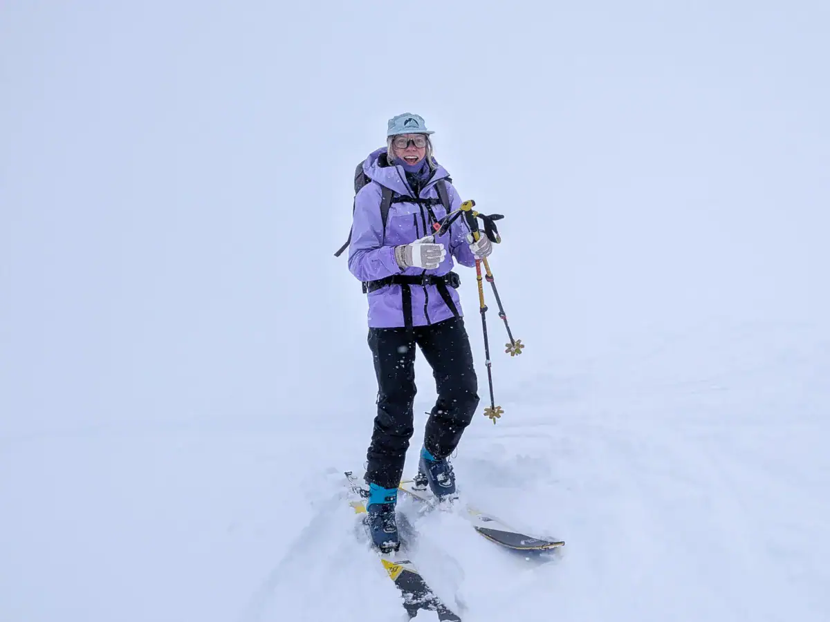 female skier smiling at the camera in a whiteout