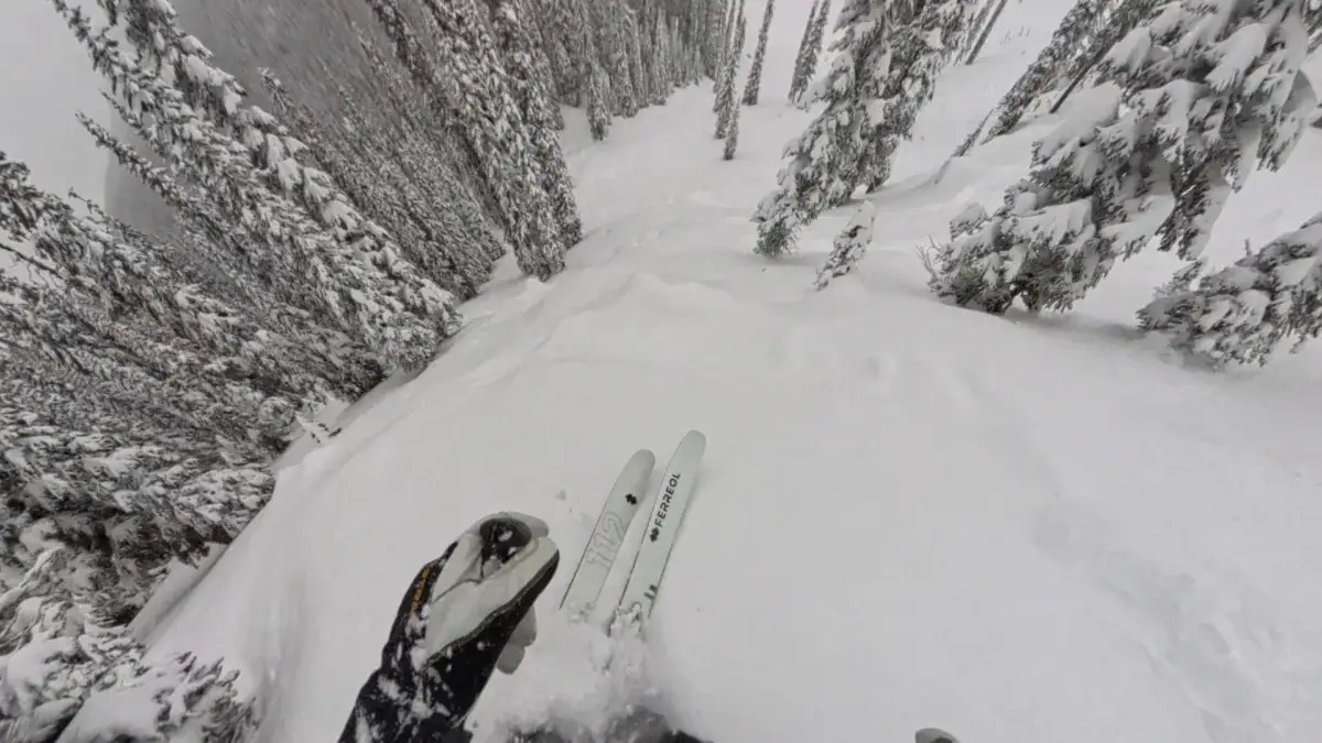 first person perspective of skier racing down a treed run in the winter