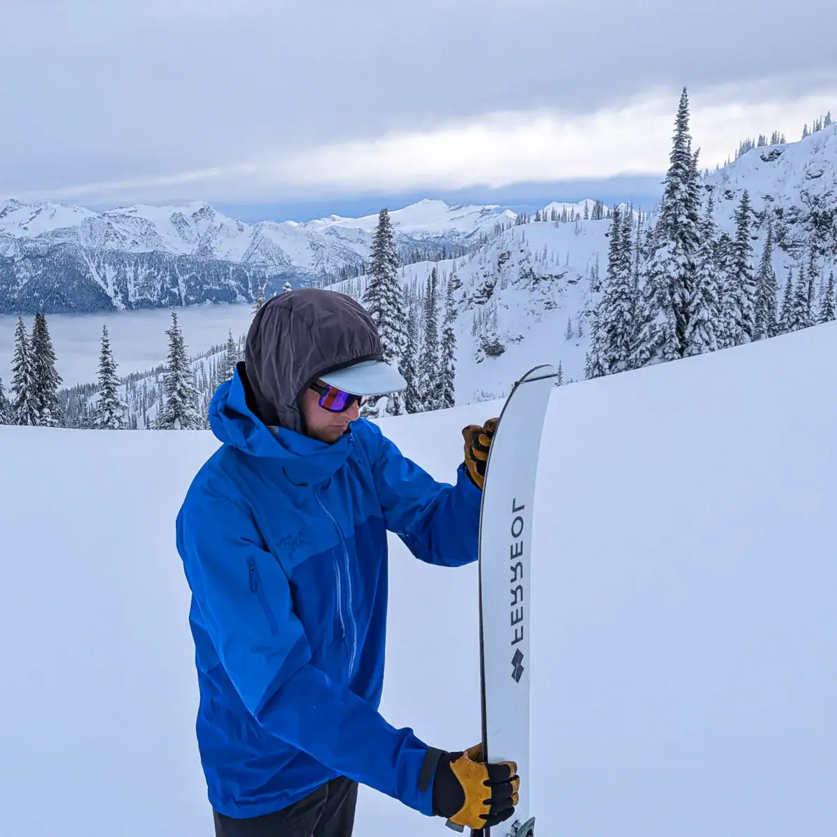 skier adhering skins to skis below montana peak